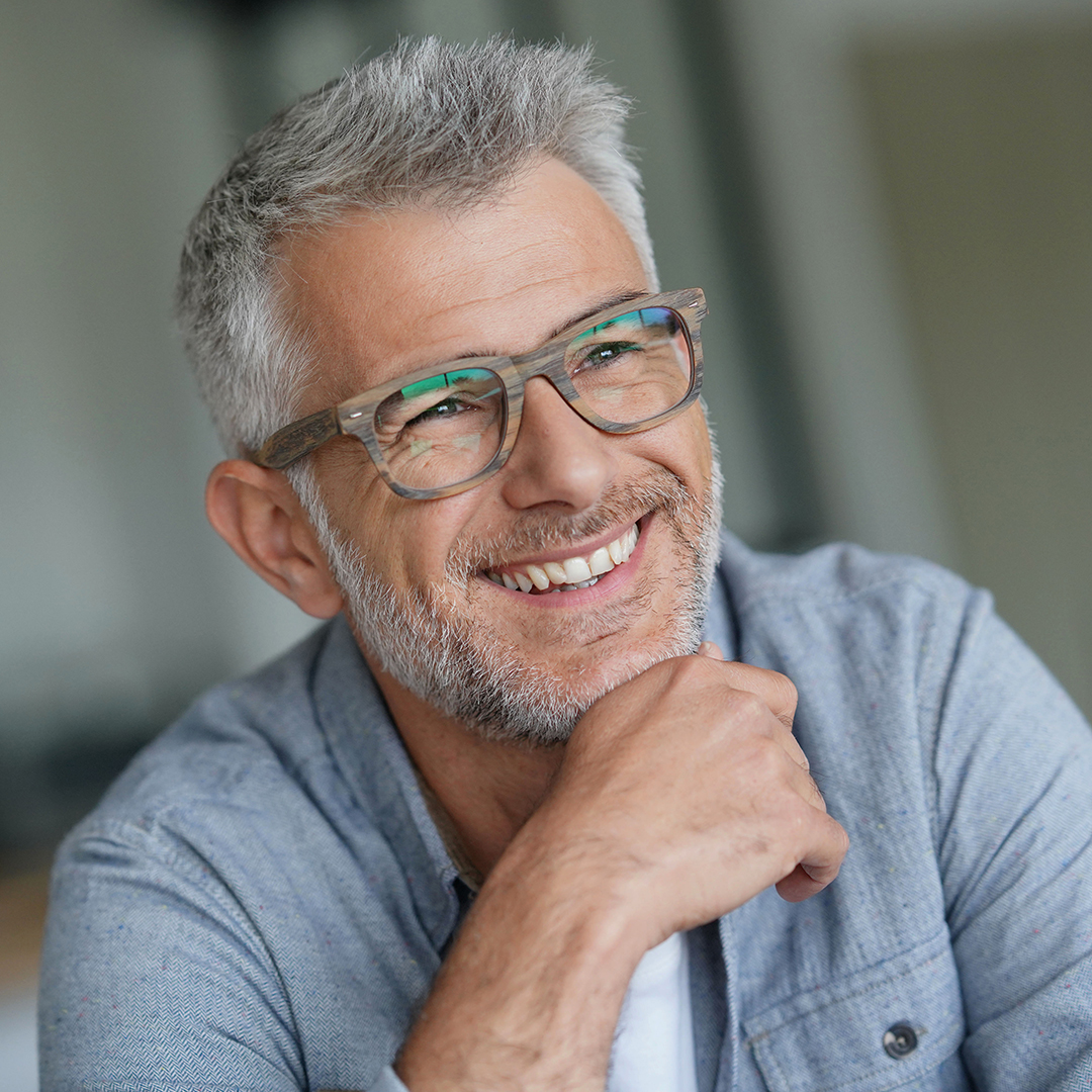 Um homem simpático de óculos e barba grisalha sorrindo.